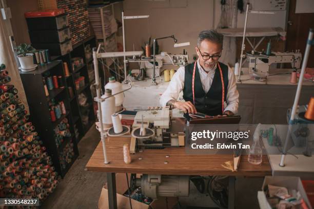 high angle asian chinese senior tailor video call discussion with customer with digital tablet at his  atelier studio - new normal concept stock pictures, royalty-free photos & images