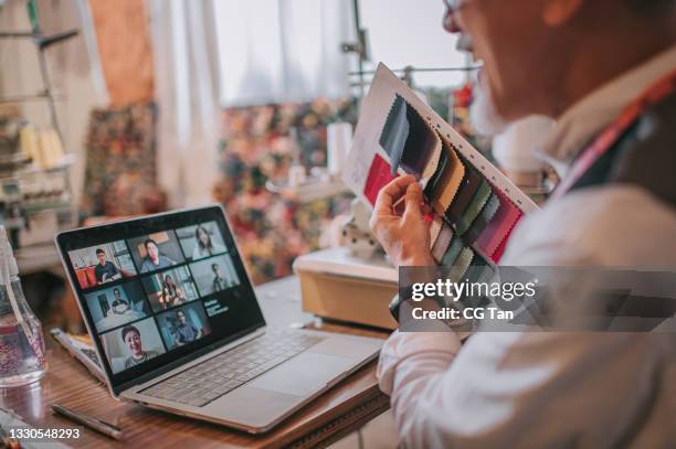 looking over shoulder asian chinese senior man showing fabric swatch video call student with digital tablet conducting online education class at his studio - flexible screen stock pictures, royalty-free photos & images