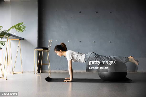 young woman doing yoga using ball - fitness ball imagens e fotografias de stock
