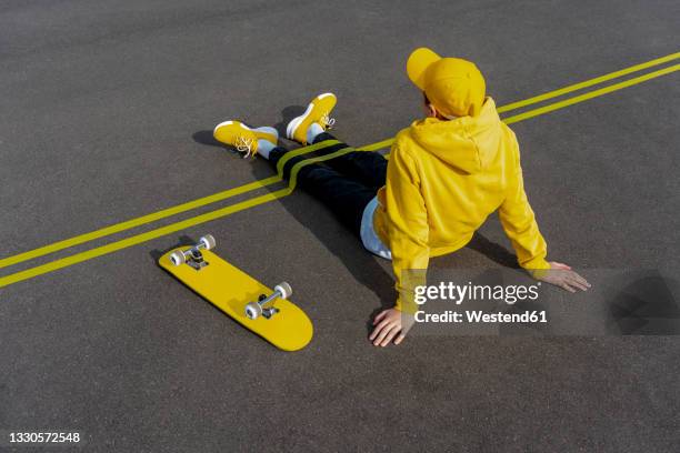 yellow adhesive tapes over boy's legs by skateboard on road - boy yellow shirt stock pictures, royalty-free photos & images