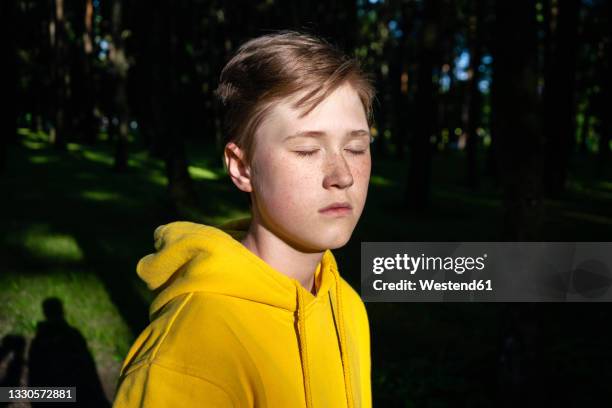 sunlight on boy with eyes closed - boy yellow shirt stock pictures, royalty-free photos & images