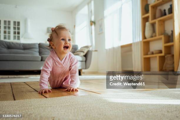 cute baby girl looking away while crawling at home - de quatro - fotografias e filmes do acervo