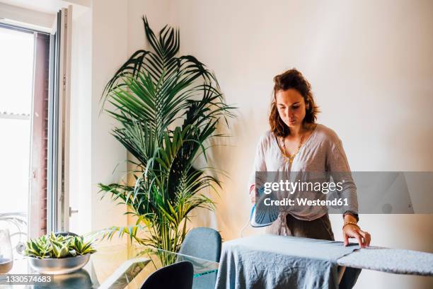 woman ironing at home - stereotypical housewife stock-fotos und bilder