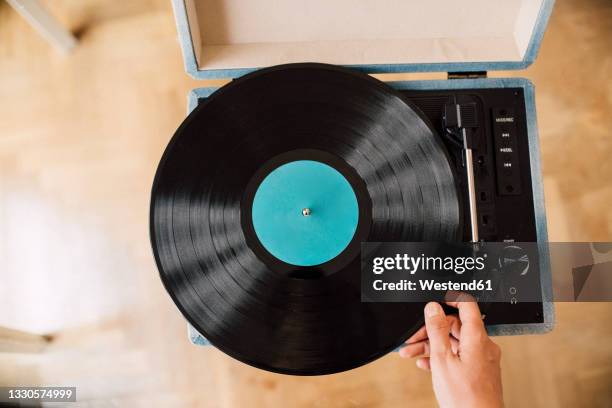 musician holding record on turntable at home - vinylplaat stockfoto's en -beelden