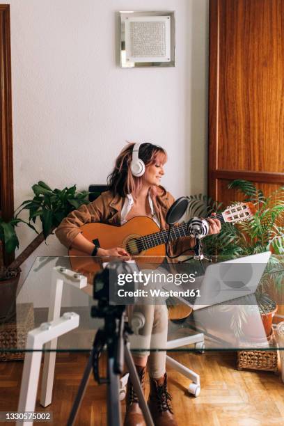 woman playing guitar while filming at home - vocal guitar stock-fotos und bilder