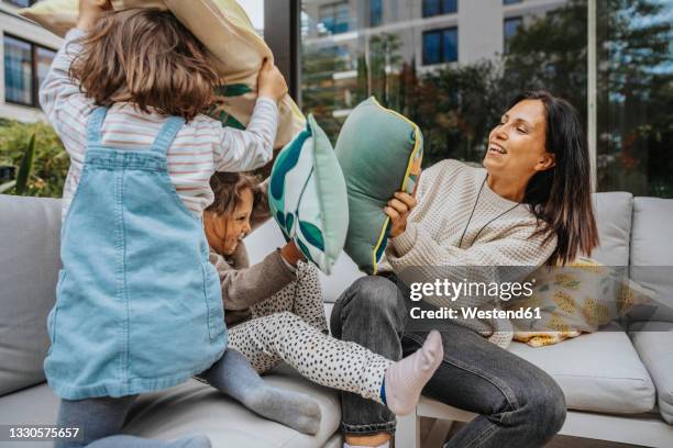 mother and daughters doing cushion fighting at backyard - cushion photos et images de collection