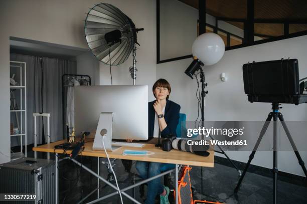 female photographer sitting at desk in studio - front flash photography foto e immagini stock