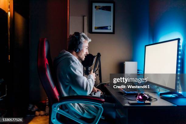 gamer doing online streaming while playing game on computer at home - gamers stockfoto's en -beelden