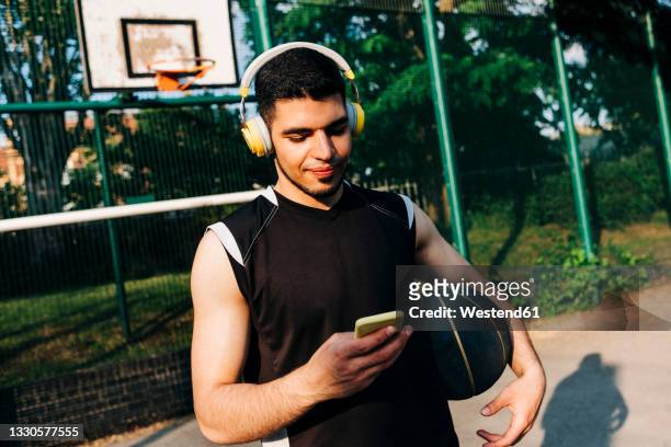 basketball player listening music on headphones on court - court hearing stockfoto's en -beelden