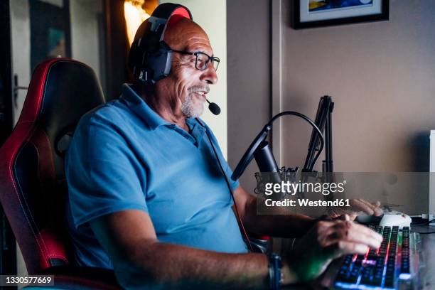 senior man doing online streaming while playing video game at home - old pc stock pictures, royalty-free photos & images