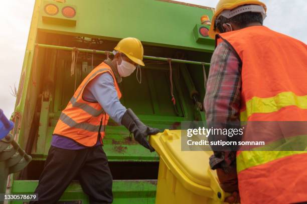 angle shot garbage collector at teamwork - rubbish lorry stock pictures, royalty-free photos & images