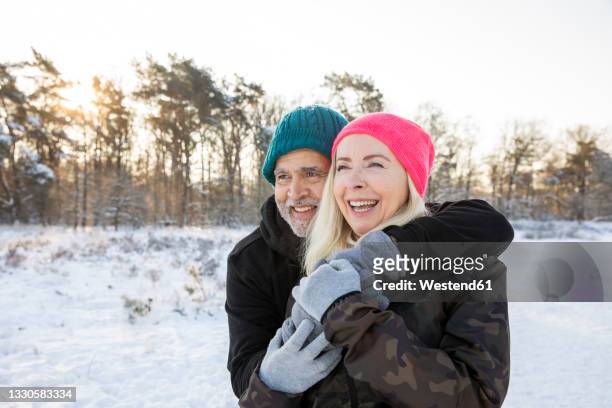 cheerful senior couple standing together during winter - man standing in the snow stock-fotos und bilder