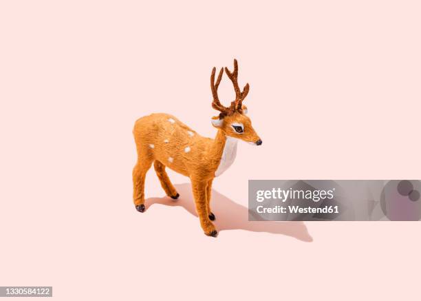 studio shot of reindeer figurine standing against pink background - single object stock pictures, royalty-free photos & images