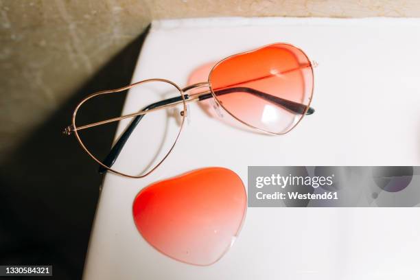 broken orange heart shape sunglasses on table - brille kaputt stock-fotos und bilder