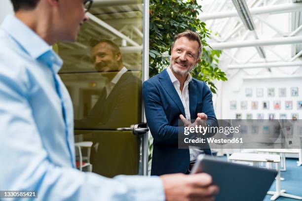 smiling businessman having discussion with colleague at office - office cabin ストックフォトと画像