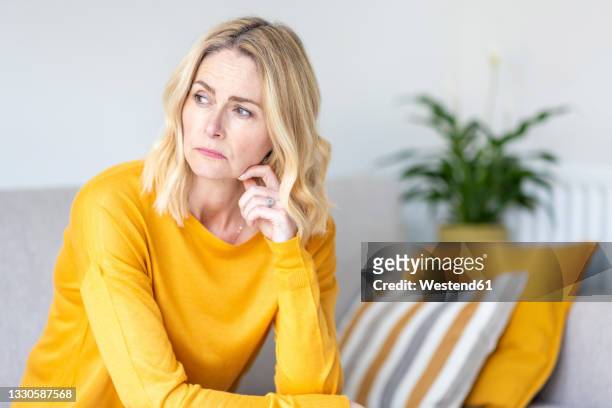 thoughtful woman looking away while sitting at home - depression sadness stock pictures, royalty-free photos & images