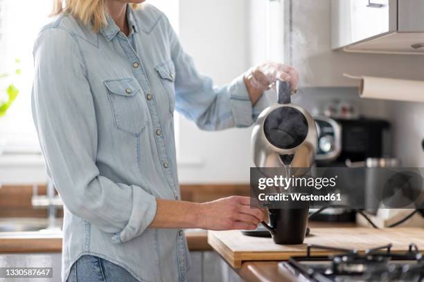 woman preparing tea in kitchen at home - kettle steam stock pictures, royalty-free photos & images