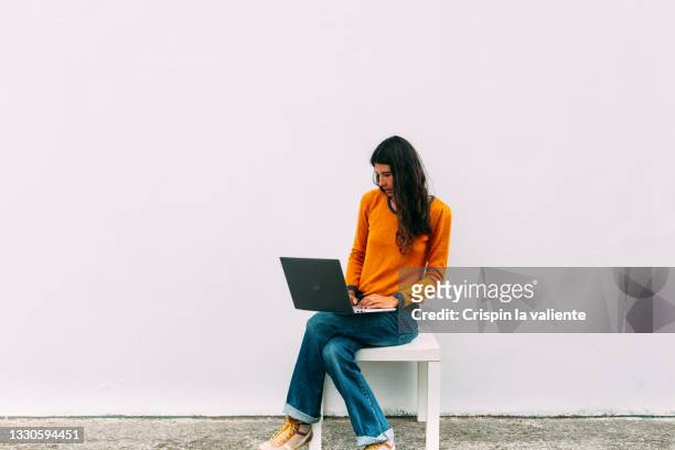full-length portrait of modern young woman sitting using laptop - beautiful woman 35 sit studio stock-fotos und bilder