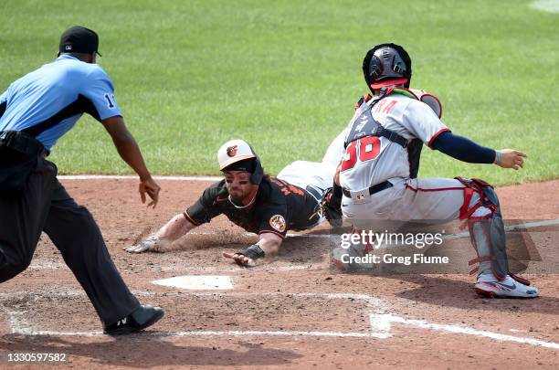 Ryan McKenna of the Baltimore Orioles slides into home plate and scores the winning run in the ninth inning ahead of the tag of Tres Barrera of the...