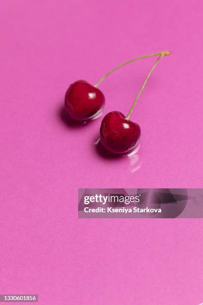 two cherries lie on a pink background - cherry on top stock-fotos und bilder