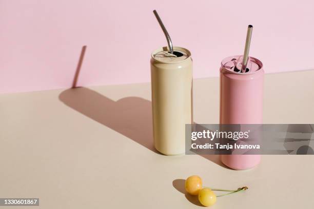 pink and beige aluminum drink can with reusable stainless steel straws and yellow cherry berries on pink beige background. minimal art still life. zero waste, plastic free concept. - estaño fotografías e imágenes de stock