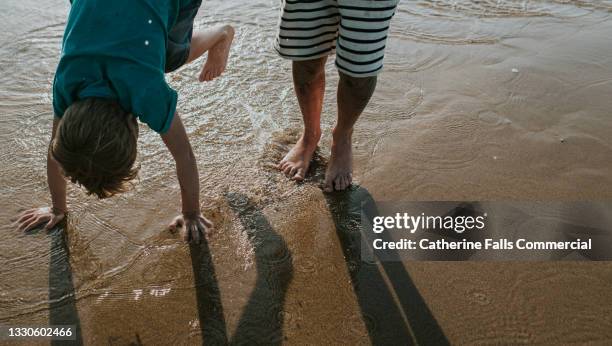 children paddle in high tide in the evening - ankle deep in water - fotografias e filmes do acervo