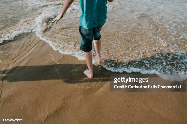 child paddles into the ocean - knöcheltief im wasser stock-fotos und bilder