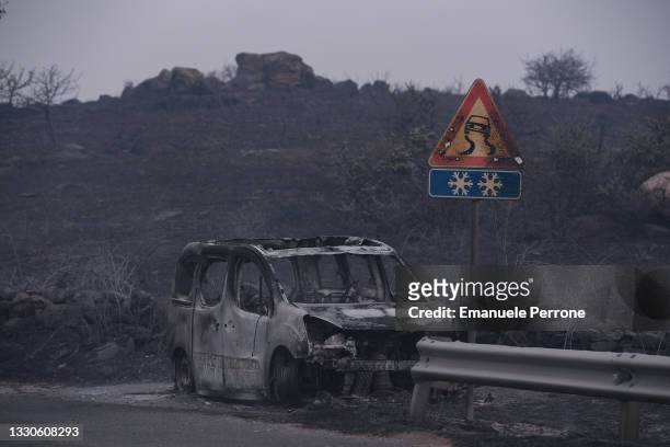 Car is left destroyed by the blaze that has raced through thousands of hectares of land on July 25, 2021 in the province of Oristano in Sardinia,...