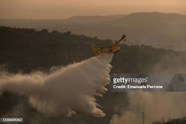Tanker plane drops water on a blaze that has destroyed thousands of hectares of land on July 25, 2021 in the province of Oristano in Sardinia, Italy....