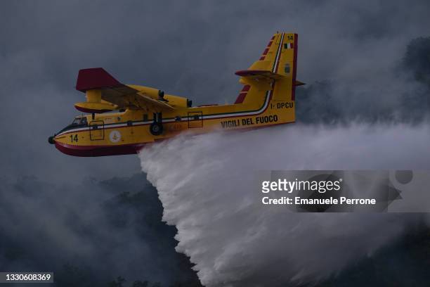 Tanker plane drops water on a blaze that has destroyed thousands of hectares of land on July 25, 2021 in the province of Oristano in Sardinia, Italy....