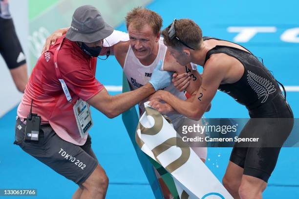 Gold medalist Kristian Blummenfelt of Team Norway is helped up by bronze medalist Hayden Wilde of Team New Zealand following the Men's Individual...
