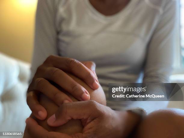 black woman experiences knee pain - woman holding legs fotografías e imágenes de stock