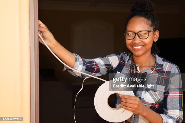 weather stripping african american woman smiles at camera - weather stripping stock pictures, royalty-free photos & images