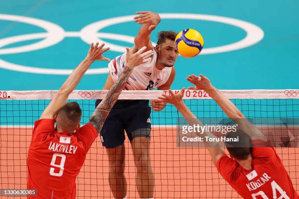 Torey Defalco of Team United States hits between Ivan Iakovlev of Team ROC and Igor Kobzar during the Men's Preliminary Round - Pool B volleyball on...