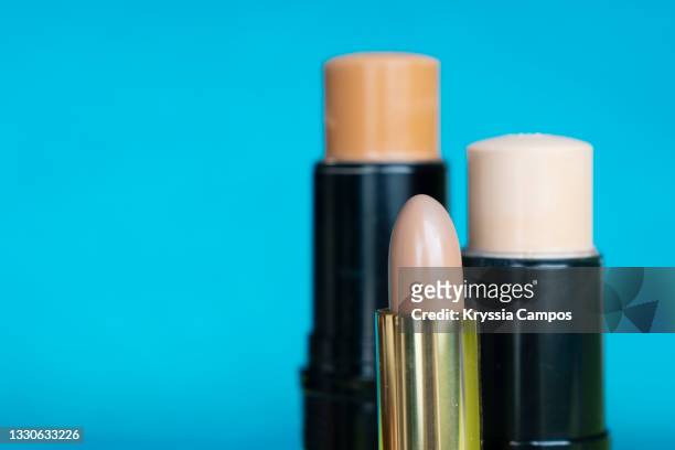 bronzer and concealer foundation sticks against blue background, copy space - concealer stock pictures, royalty-free photos & images