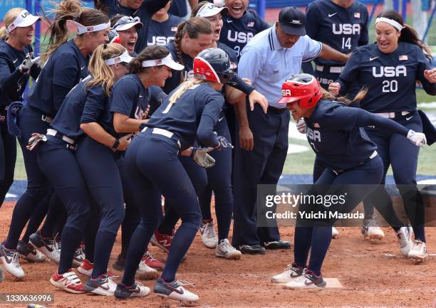 Kelsey Stewart of Team United States jumps on home plate as the umpire and her teammates watch her score the winning run after Stewart hit a walk-off...