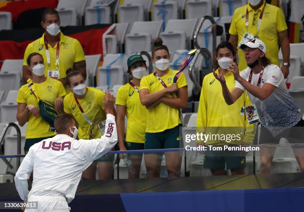 Caeleb Dressel of Team United States tosses his medal to Brooks Curry of Team United States after winning the Men's 4 x 100m Freestyle Relay Final on...