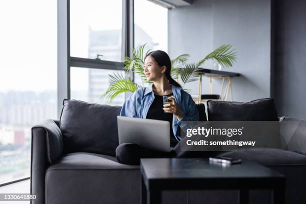 asian women working at home - businesswoman couch stock pictures, royalty-free photos & images