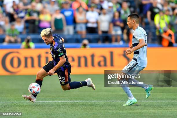 Kelyn Rowe of Seattle Sounders drives the ball against Daniel Salloi of Sporting Kansas City during the game at Lumen Field on July 25, 2021 in...