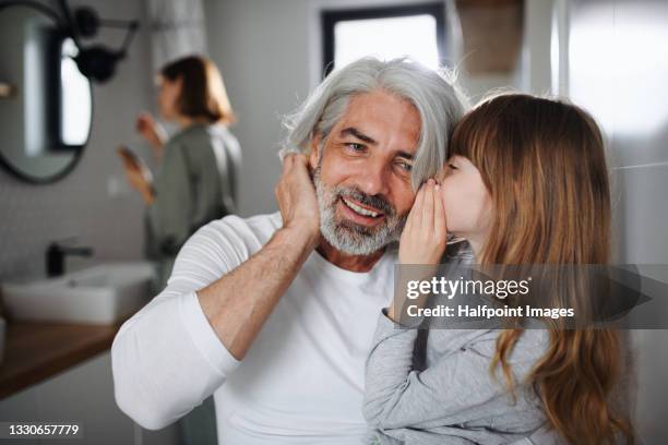 portrait of mature father with small daughter in bathroom indoors at home, talking. - weitersagen stock-fotos und bilder