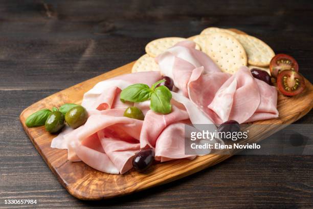 italian parma ham prosciutto cotto with olives on a wooden board - parmaschinken stock-fotos und bilder