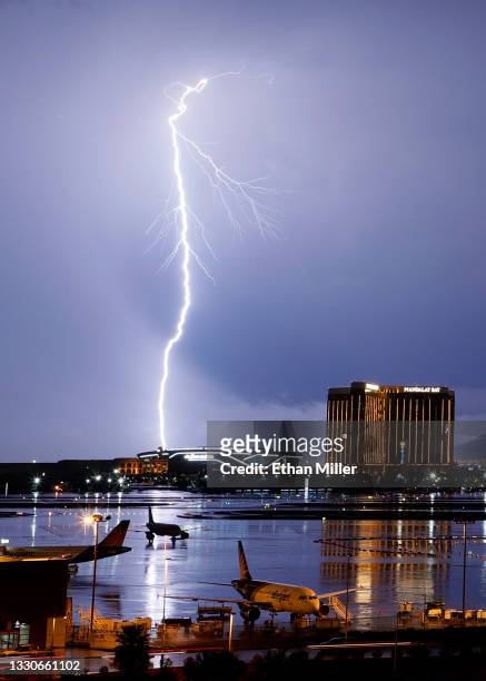 Airplanes are shown parked at McCarran International Airport as lightning strikes west of Allegiant Stadium and Mandalay Bay Resort and Casino during...