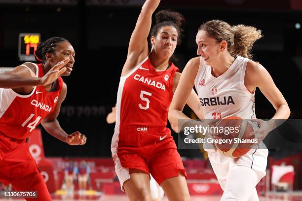 Aleksandra Crvendakic of Team Serbia drives to the basket against Kayla Alexander and Kia Nurse of Team Canada during the first half of the Women's...