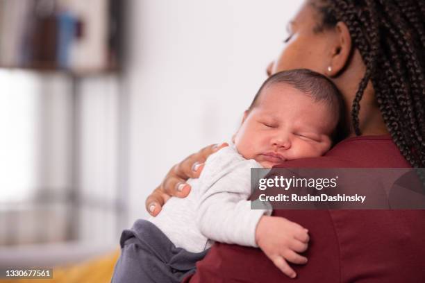 bebé acostado sobre el hombro de la madre. - black mother holding newborn fotografías e imágenes de stock