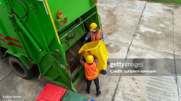 garbage collector at teamwork and garbage truck - vuilnisman stockfoto's en -beelden