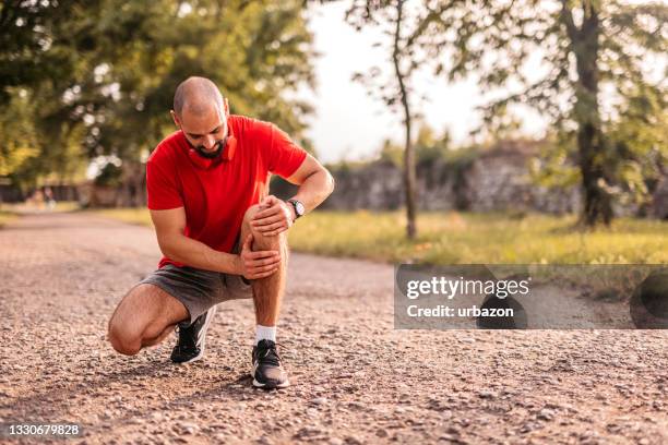 deportista lastimándose la rodilla durante la carrera - arrodillarse fotografías e imágenes de stock