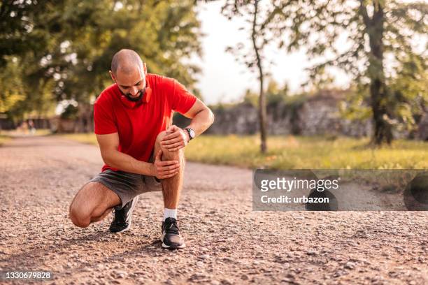 sportsman hurting his knee during running - muscle cramps stock pictures, royalty-free photos & images