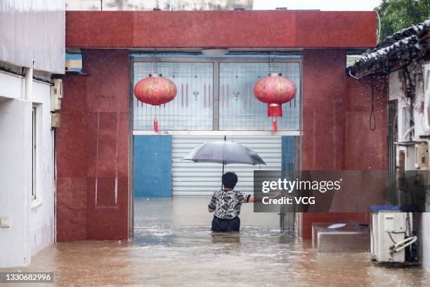 Local resident with an umbrella wades in a flooded street on July 25, 2021 in Ningbo, Zhejiang Province of China. Typhoon In-Fa made landfall in east...