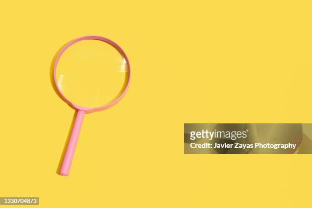 pink magnifying glass on yellow background - loupe stock-fotos und bilder