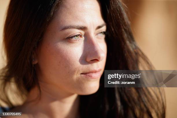 beautiful brunette with green eyes looking into distance, close-up - no make up stockfoto's en -beelden